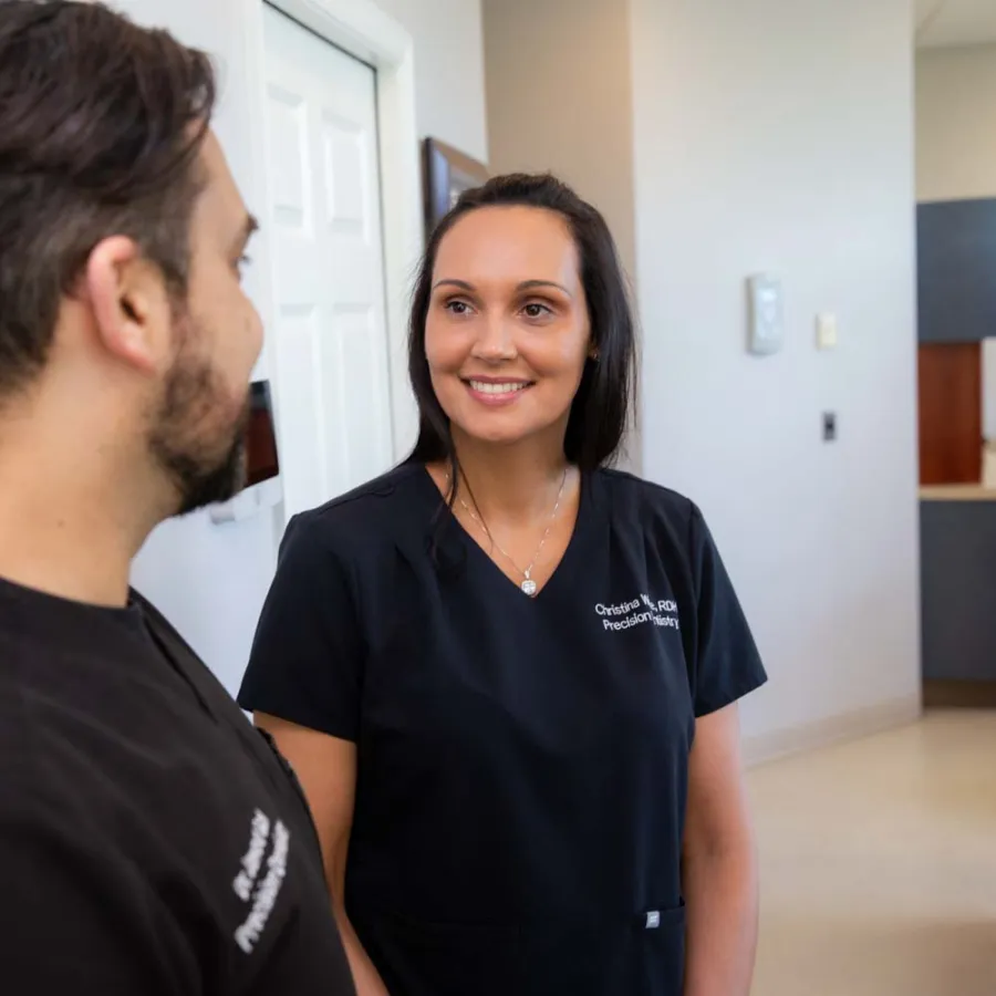 Female medical professional in black scrubs talking to male colleague in a clinical office setting