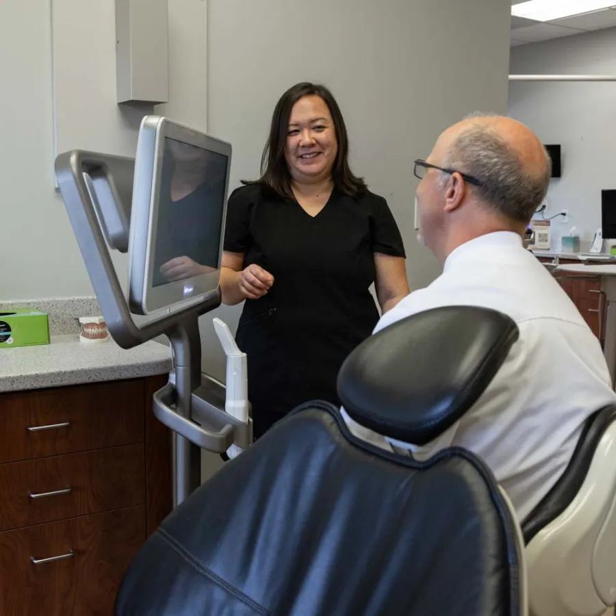 Dentist consulting a male patient in a dental clinic with modern equipment and computer screen