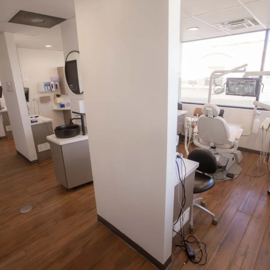 Bright dental clinic interior with multiple treatment rooms and modern equipment on wood flooring.