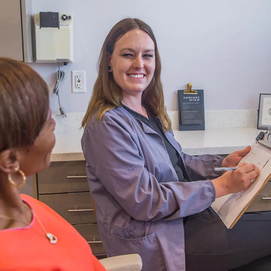Dentist explaining dental care to a patient in a modern clinic with big windows and natural light.