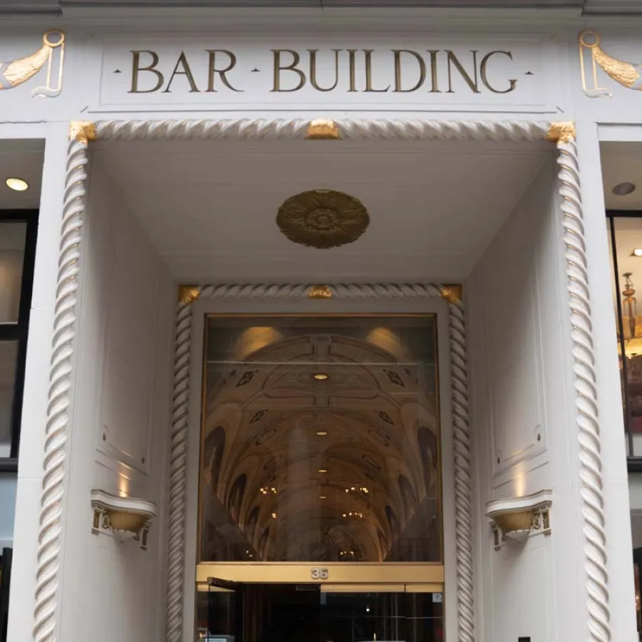 Entrance to the Bar Building with ornate white and gold detailing and a glass door beneath an arched ceiling.