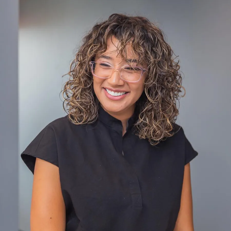 Two healthcare professionals in black scrubs smiling and discussing documents in a medical office.