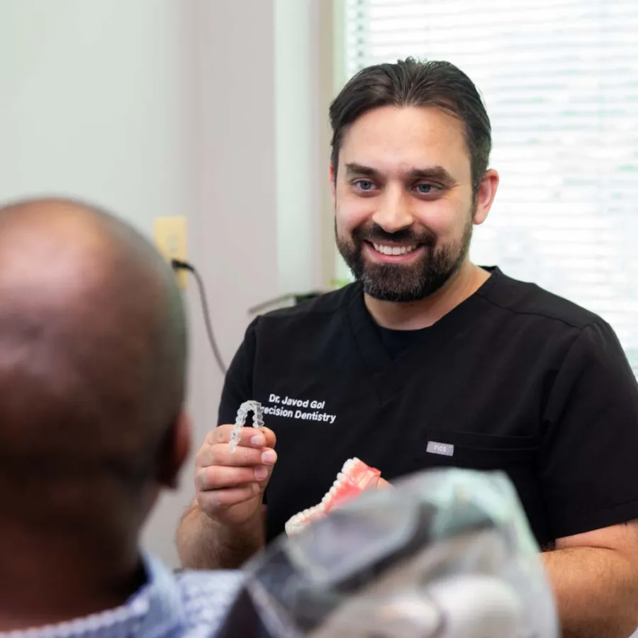 Dentist explaining dental aligners to patient in a bright dental office with smile and model teeth.