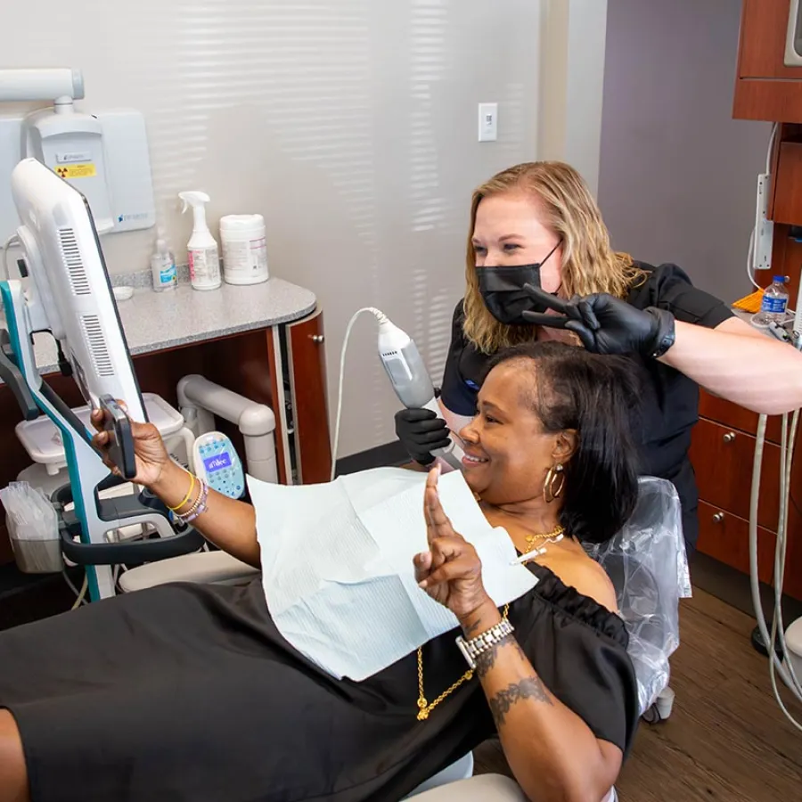 Dentist and patient smiling and posing for a selfie during dental checkup in modern clinic.