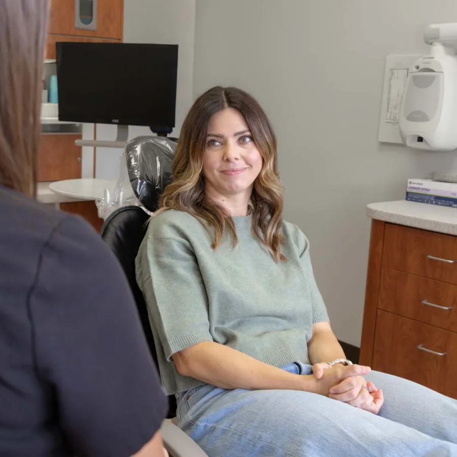 Woman sitting in dental chair smiling during consultation with dental hygienist in modern clinic.