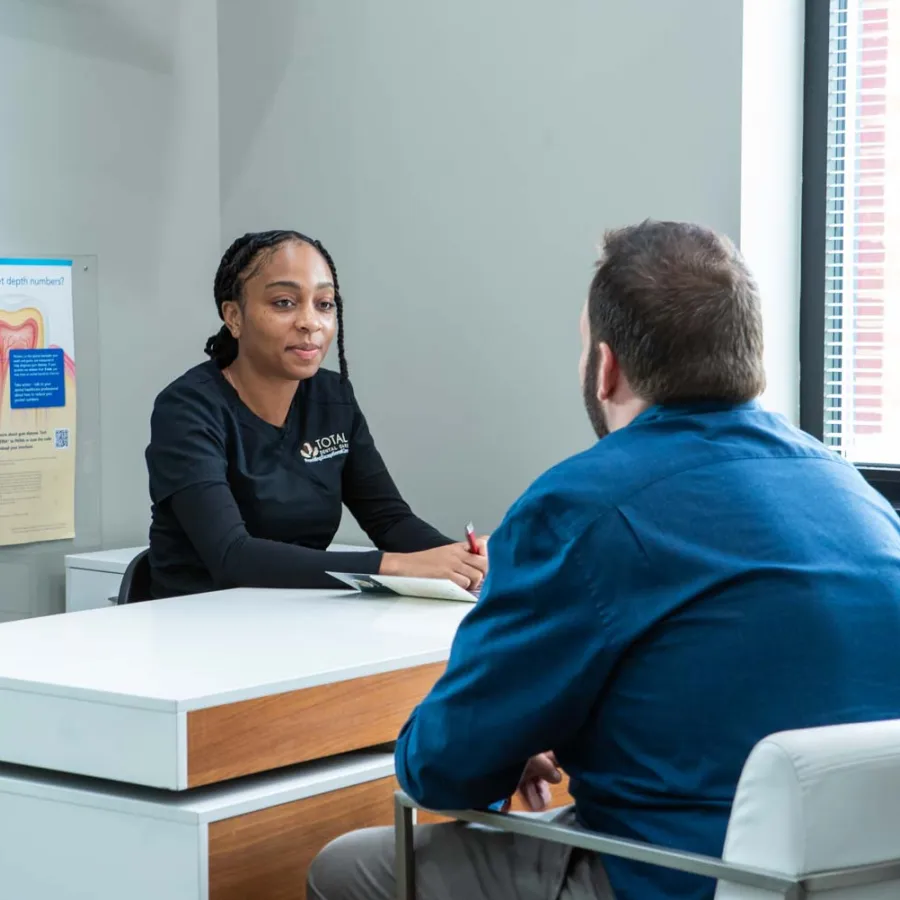 Dental professional discussing oral health with a patient in a bright, modern consultation room.