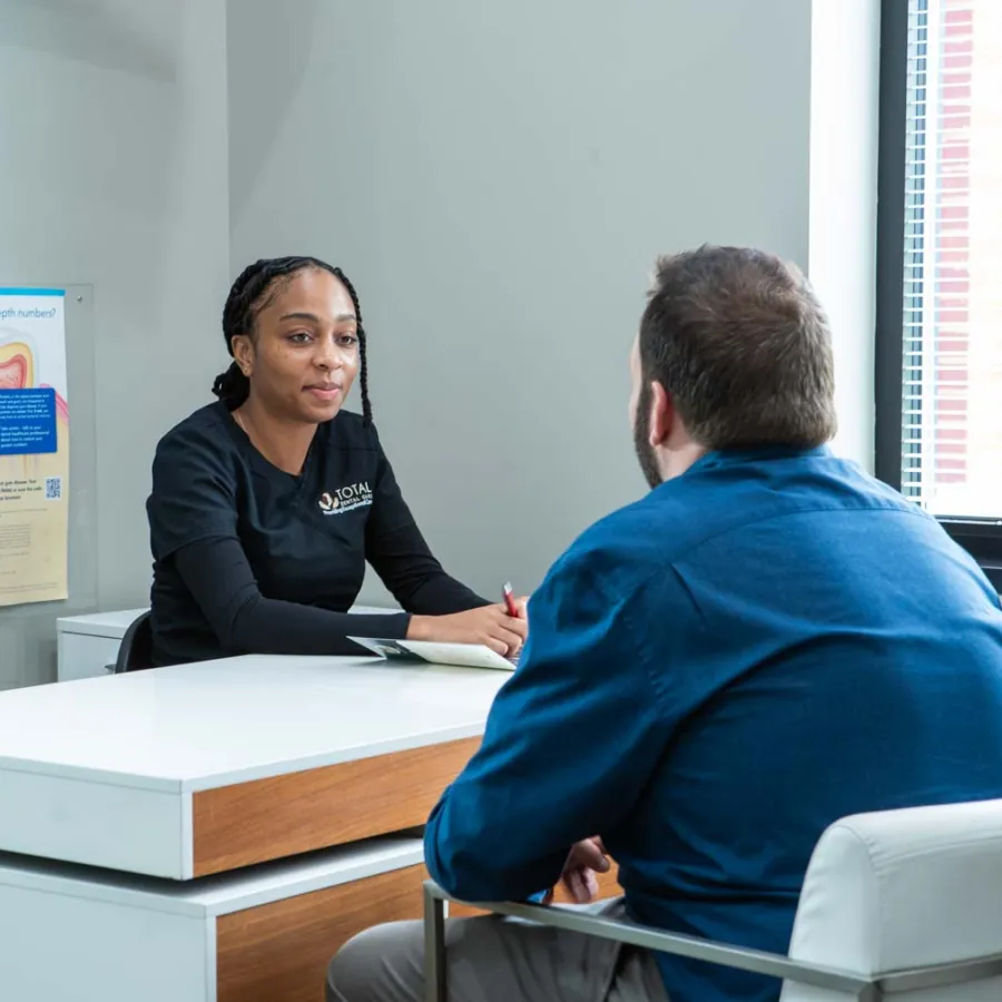 Dental professional discussing oral health with a patient in a bright, modern consultation room.