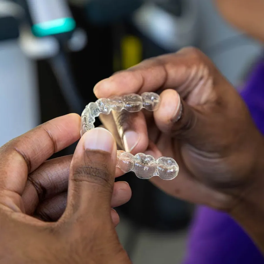 Close-up of hands holding a clear dental aligner for orthodontic teeth straightening treatment.