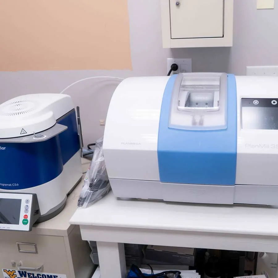 Dental milling machines with blue and white design used for precise dental restorations in a clinical setting