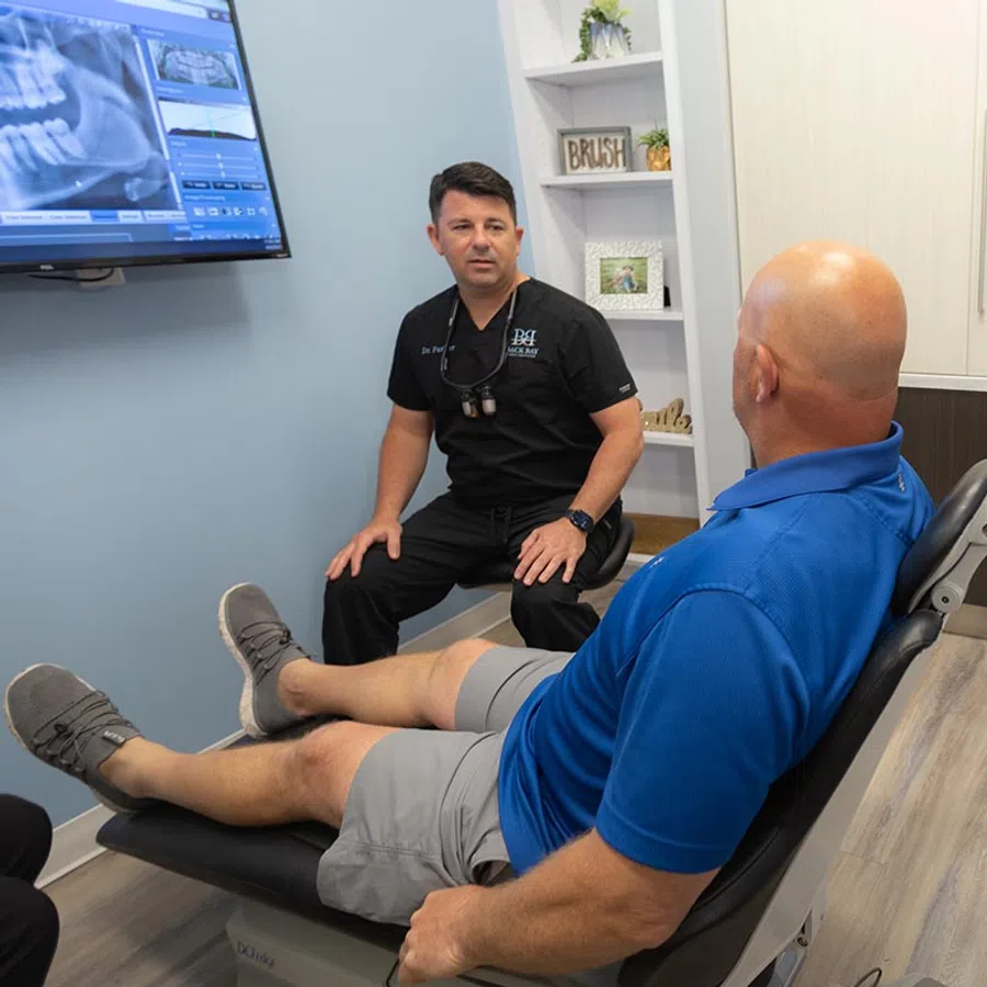 Dentist discussing dental X-ray results with patient seated in examination chair at clinic