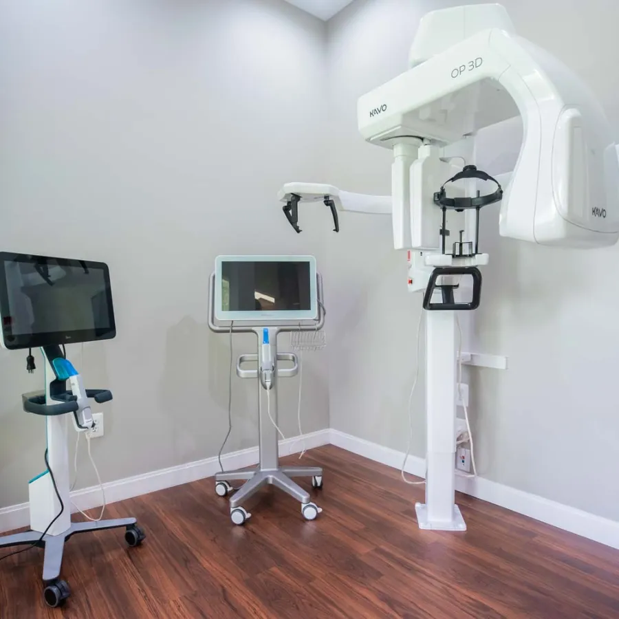 Modern dental imaging room with 3D X-ray machine and two digital monitors on mobile stands