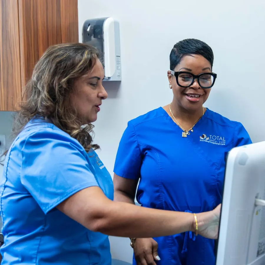 Two healthcare professionals in blue scrubs reviewing patient information on a computer in a clinical setting