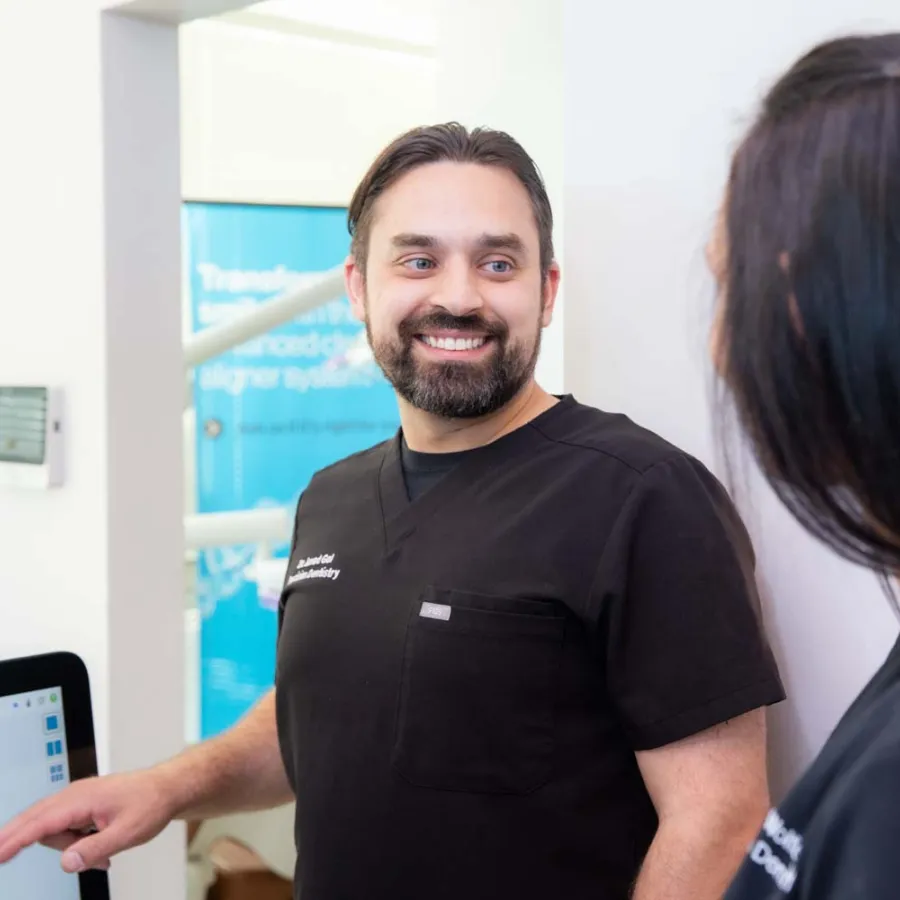 Dentist explaining dental health visuals to female patient in modern dental clinic setting.