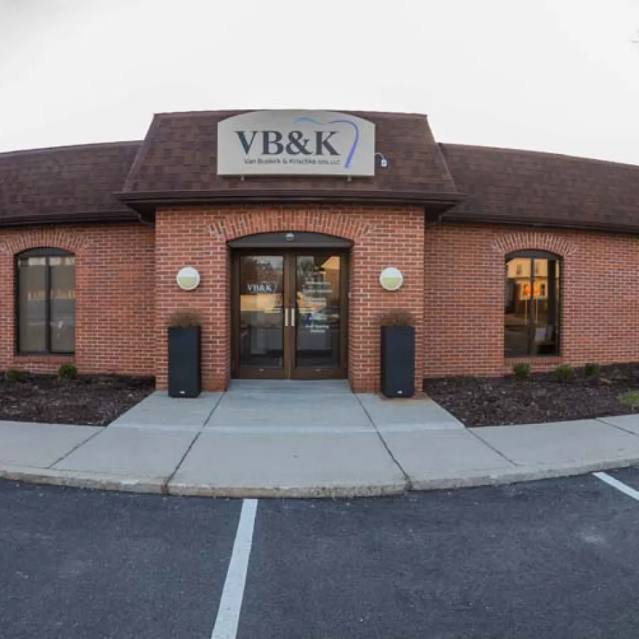 Front view of VB&K brick office building with parking lot and clear sky at sunset