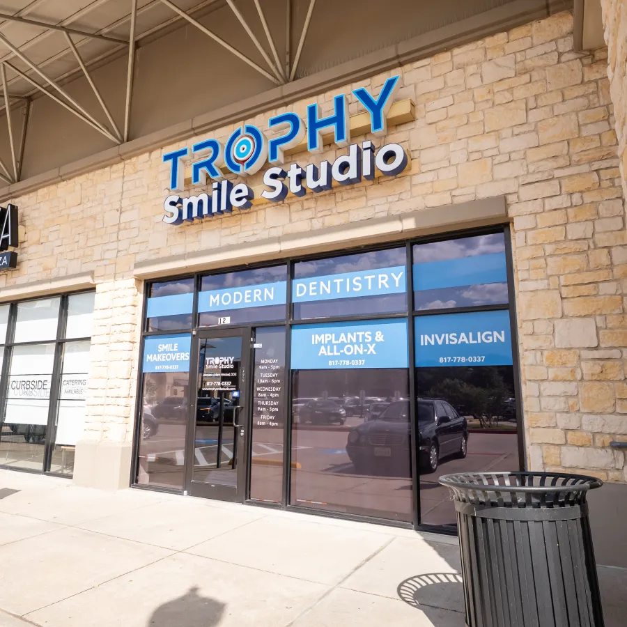 Exterior of Trophy Smile Studio dental office with modern dentistry signs and adjacent Pastaza restaurant.