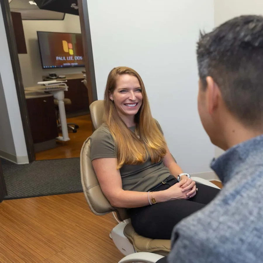 Smiling woman sitting in dental chair talking with dentist in modern dental office.