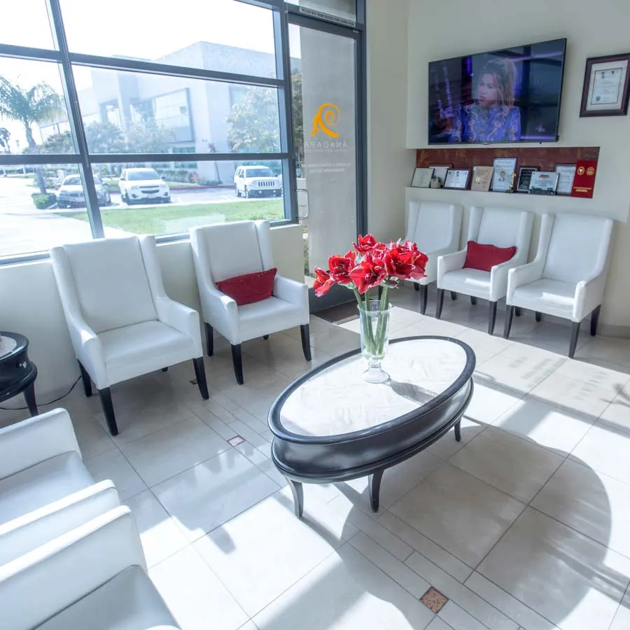 a room with white chairs and a coffee table with a vase of flowers
