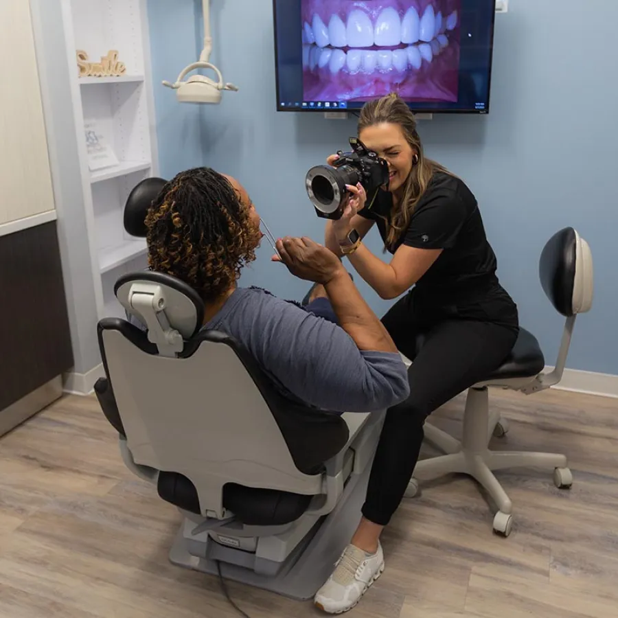 Dentist photographing patient’s teeth in dental office with teeth close-up image on screen.