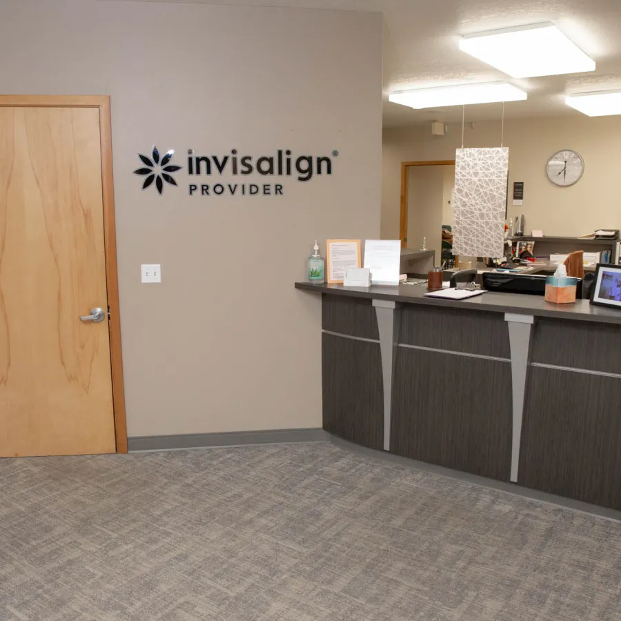 Reception area of an Invisalign provider clinic with modern desk, beige walls, and seating area.
