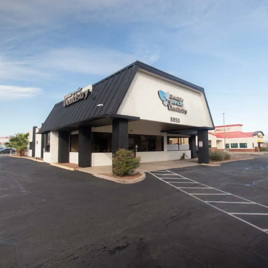 Exterior view of a modern medical center building with parking lot under a clear blue sky.