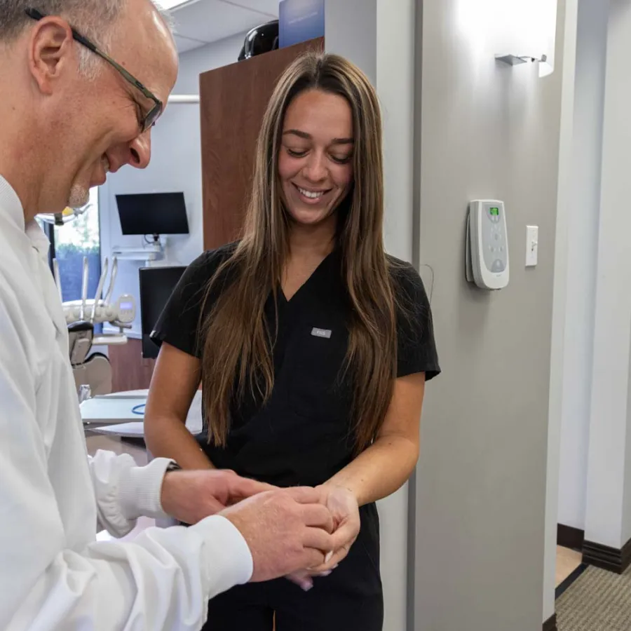 Dentist and dental assistant smiling and holding a dental mold in a modern clinic office.