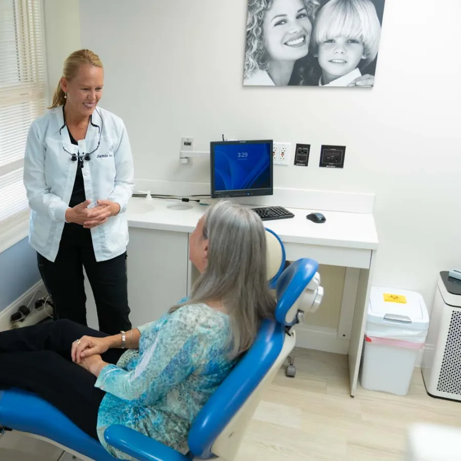 Dentist consulting with a female patient seated in a dental chair in a bright clinic room