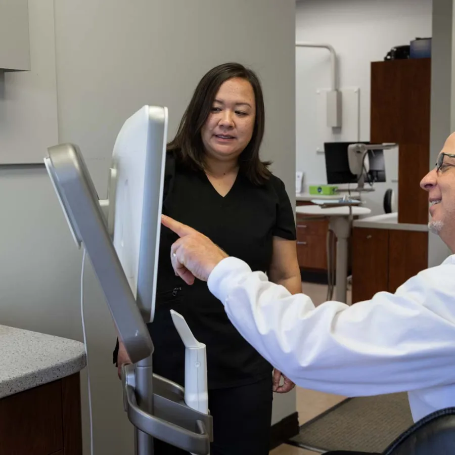 Dentist consulting with a dental assistant using a digital screen in a modern dental office.