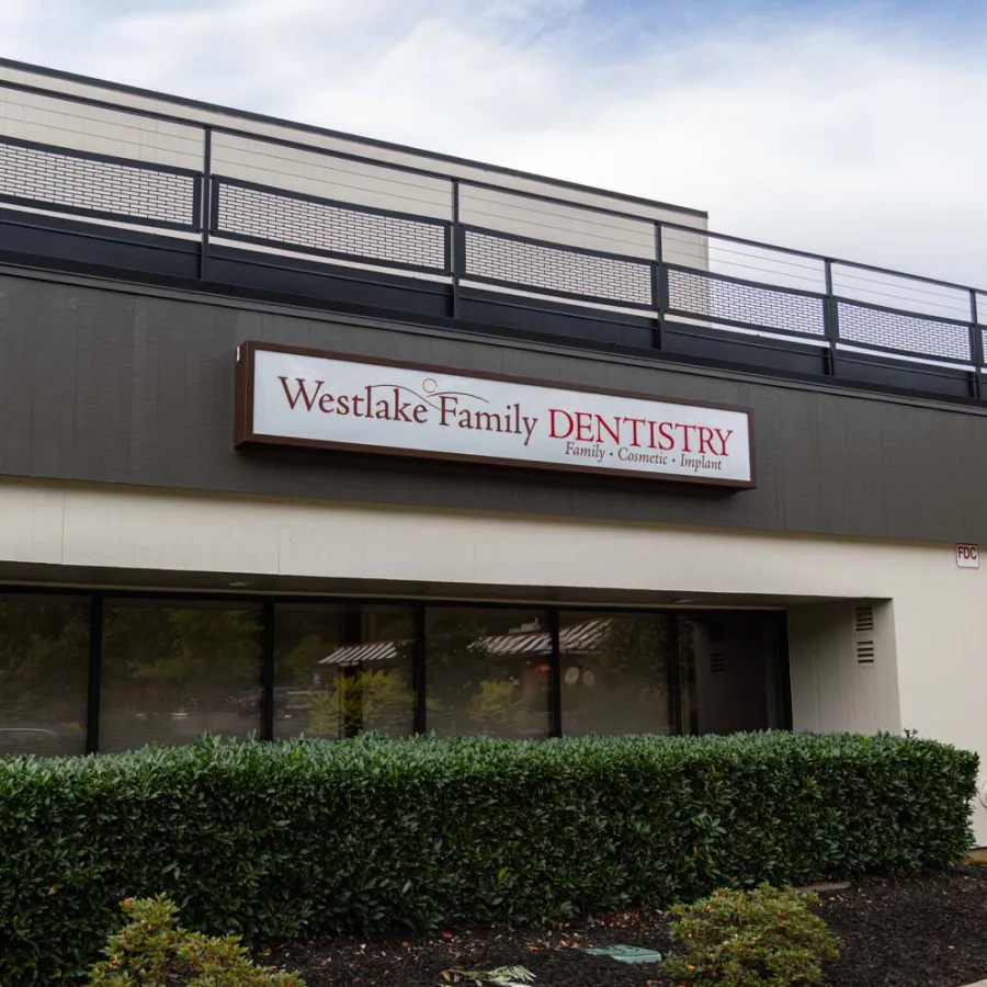 Exterior view of Westlake Family Dentistry clinic with signage and greenery under a clear sky.