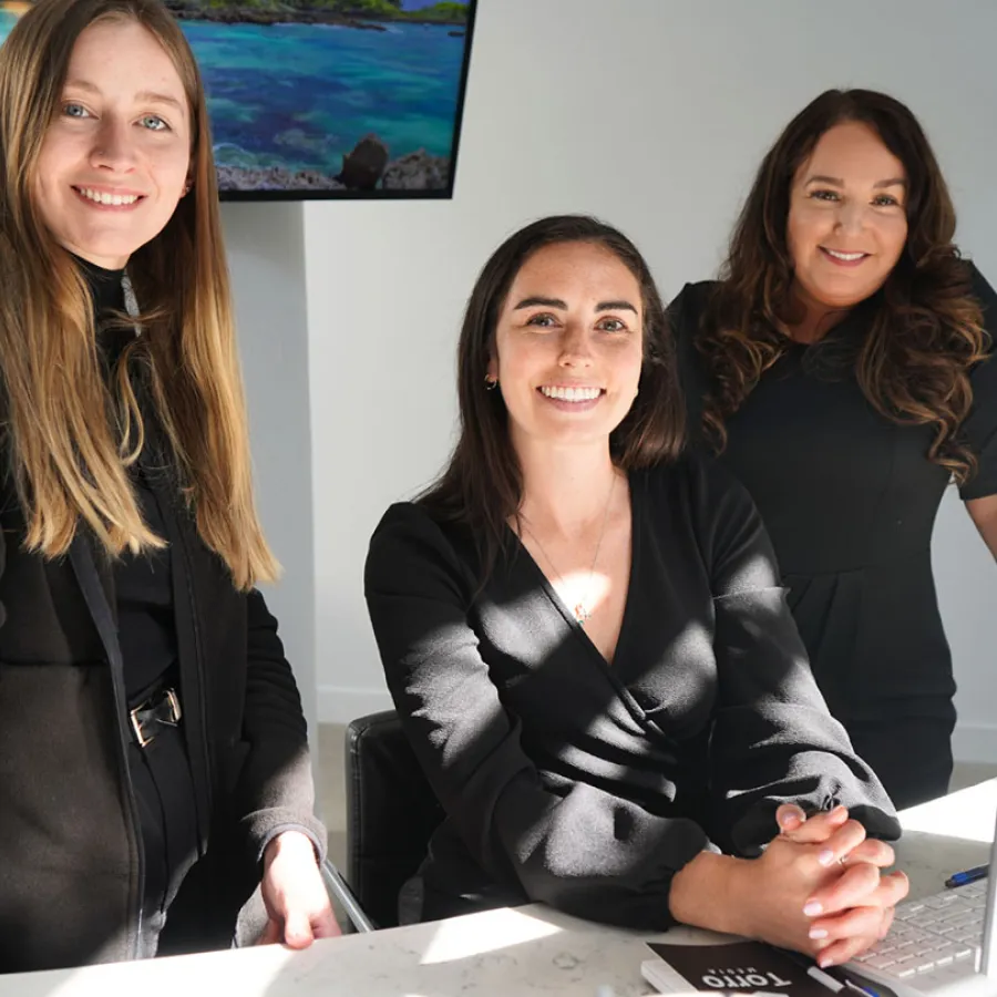 Three professional women smiling inside an office