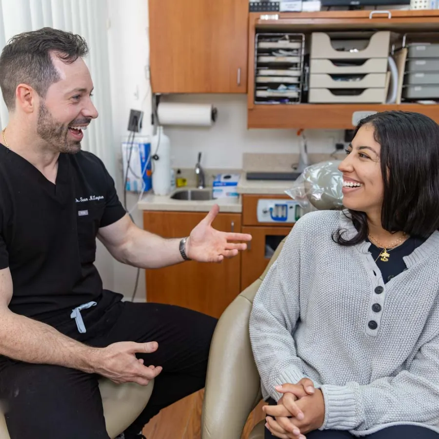 Dentist and patient smiling while discussing dental care in a bright, organized dental office.