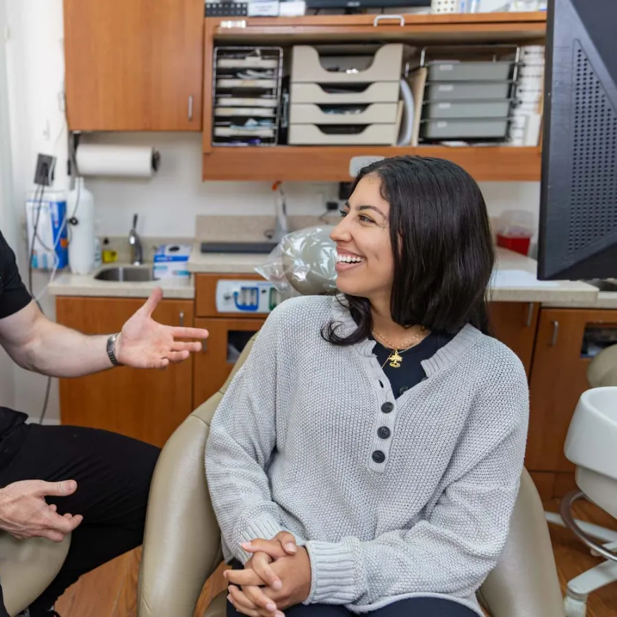 Dentist and patient smiling while discussing dental care in a bright, organized dental office.