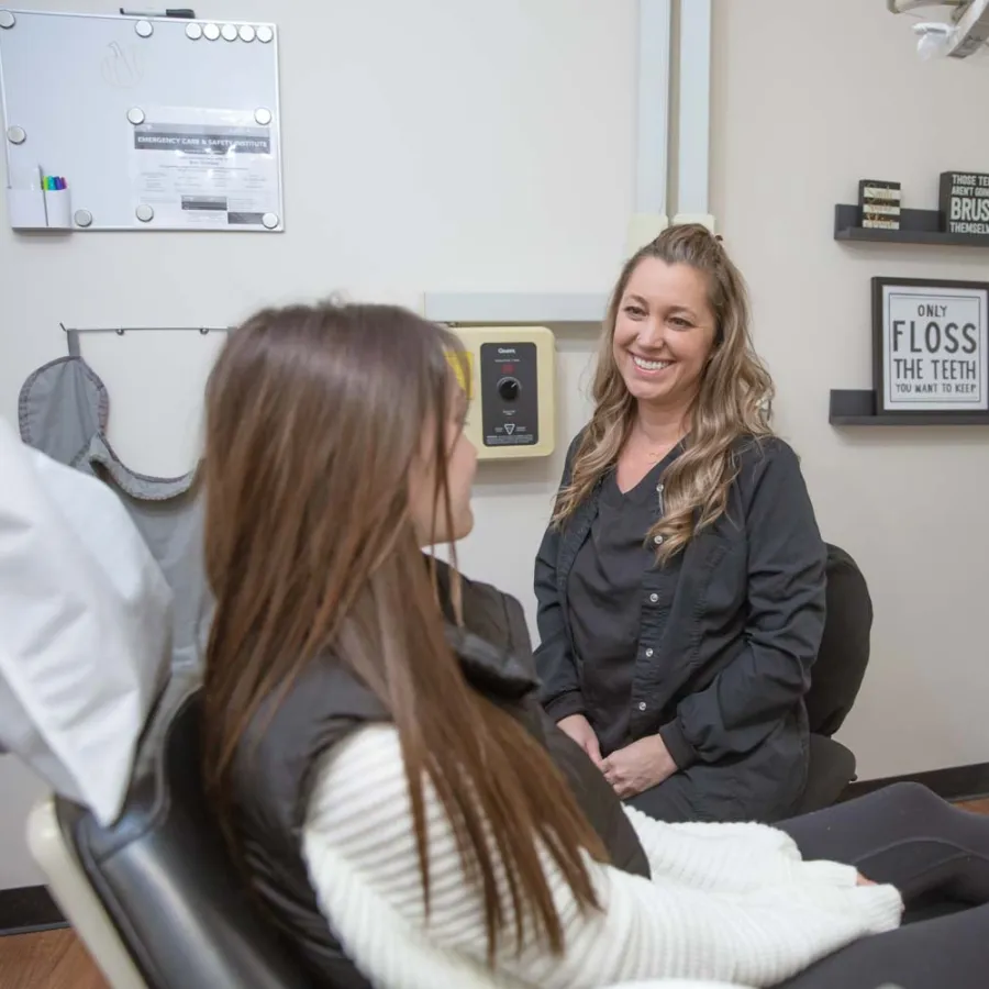 Dentist smiling and talking to female patient in a dental office with oral health decor.