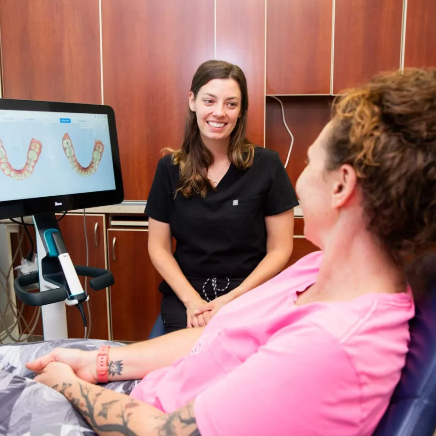 Dental professional discussing 3D teeth scan results with a patient in a modern dental office.