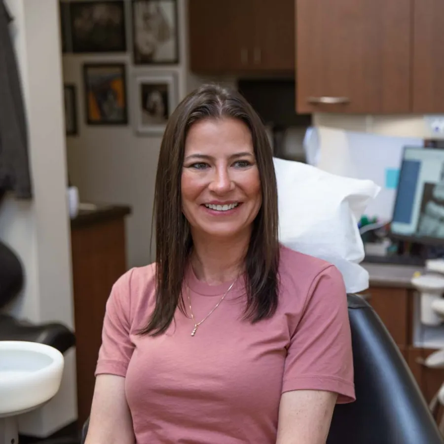 Smiling woman sitting in dental chair during consultation with dentist in modern clinic.