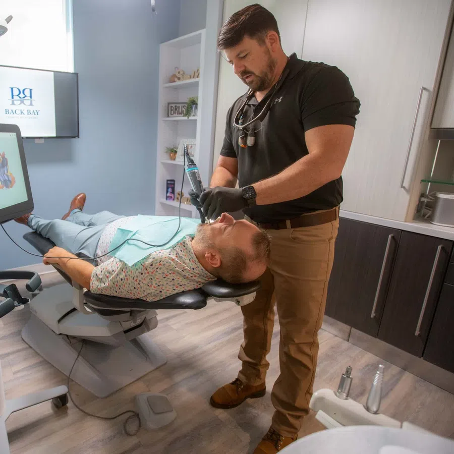 Dentist performing dental treatment on patient in modern clinic with digital imaging technology nearby