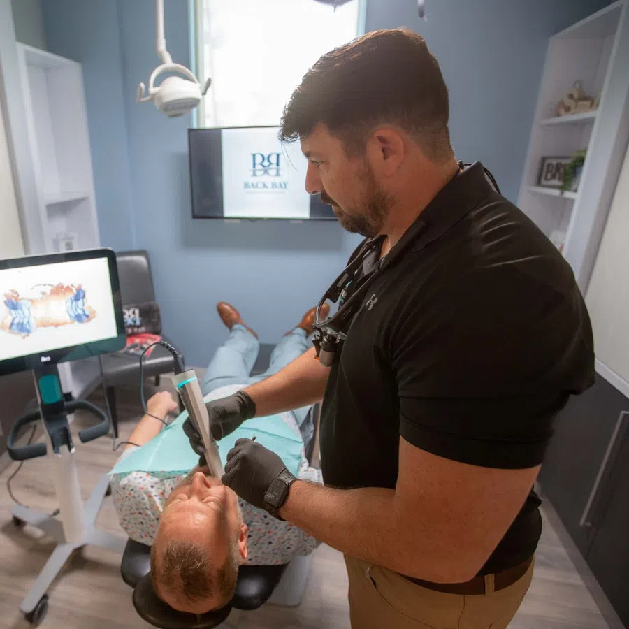 Dentist performing a dental scan on a patient in a modern dental office with digital technology.