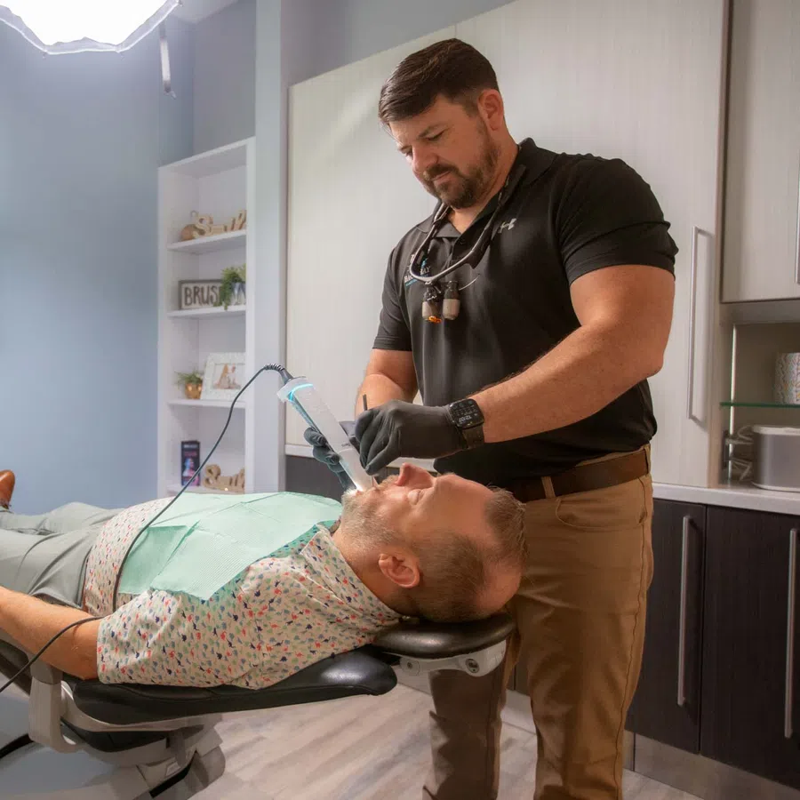 Dentist using digital scanner on patient lying in modern dental office for a 3D mouth scan
