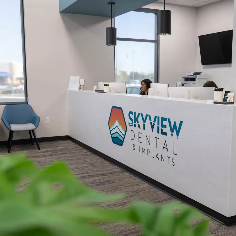 Modern dental office reception with Skyview Dental & Implants logo and seating area with blue chairs.