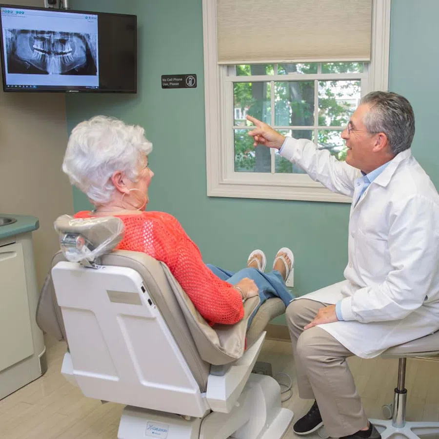 Dentist explaining dental X-ray results to senior woman patient in dental office consultation.