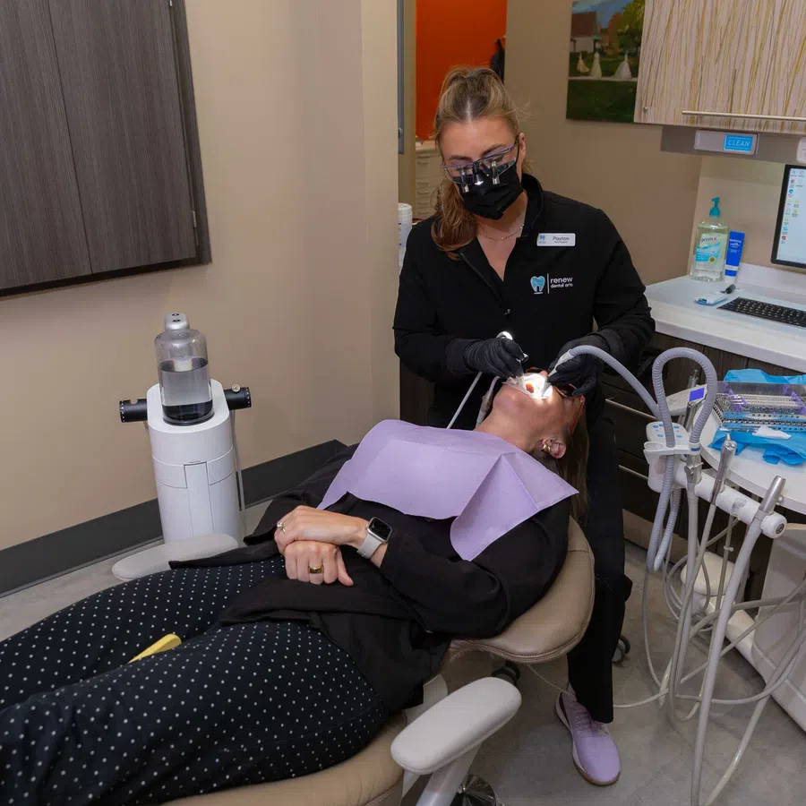 Dentist wearing black mask treating patient reclining in dental chair in modern clinic
