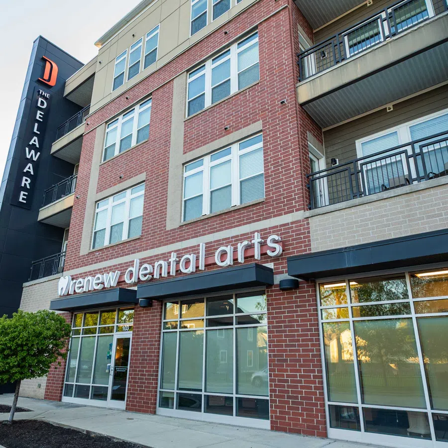 Exterior view of Renew Dental Arts clinic in a modern brick building under clear sky.