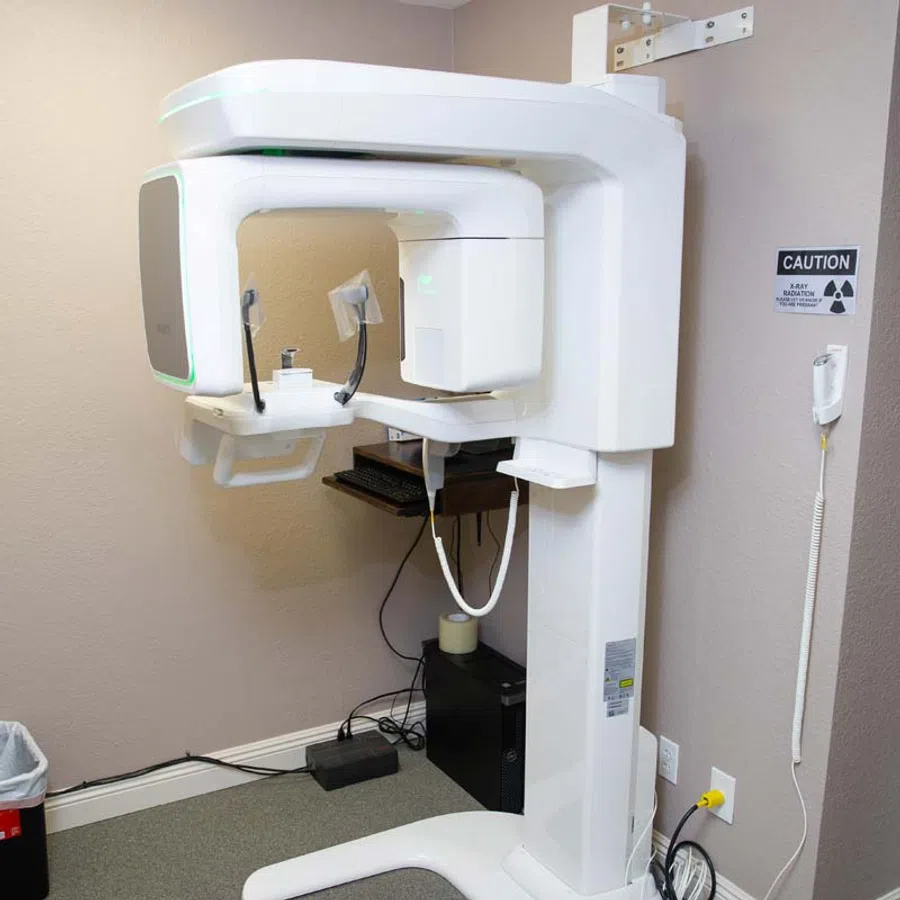 Dental panoramic X-ray machine in a clinic room with caution radiation sign on wall