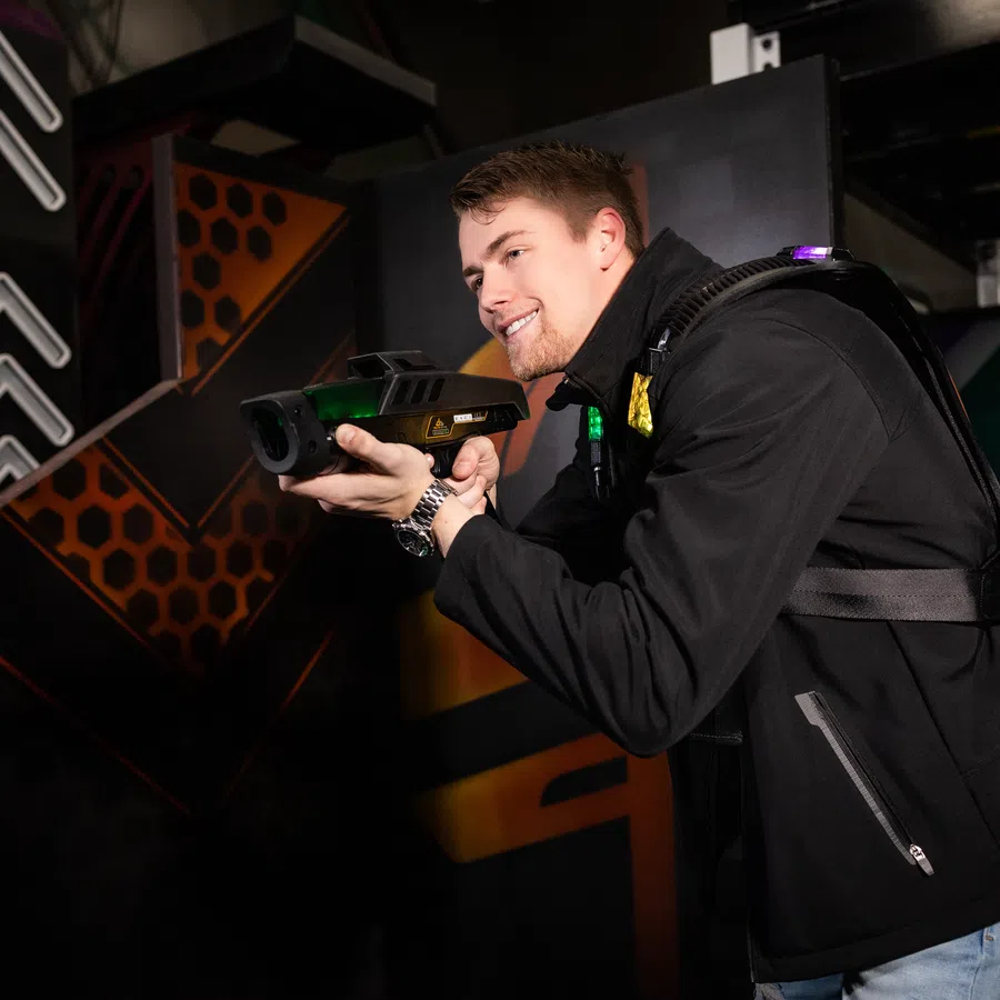 A player aiming a laser tag gun while experiencing an immersive gaming environment.