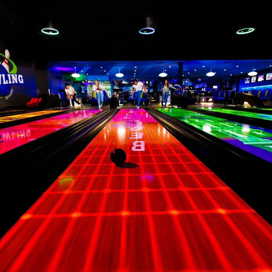 Vibrant bowling alley with neon lights and colorful lanes, capturing a lively atmosphere for bowlers.