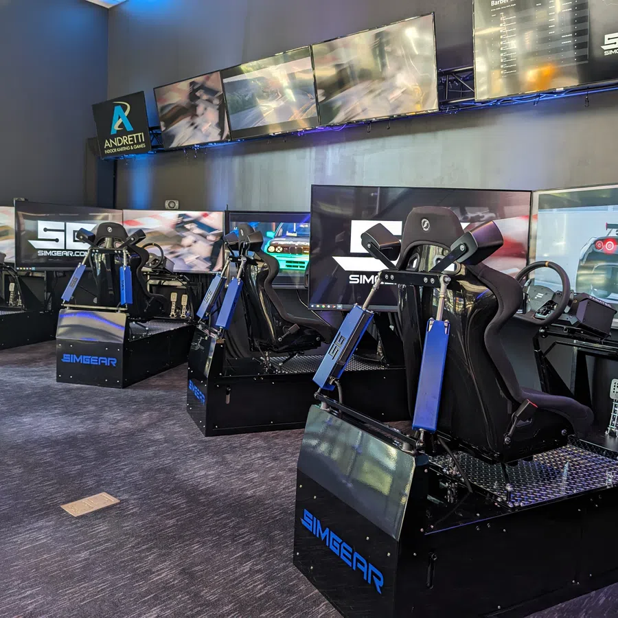 High-tech racing simulator setup with multiple screens and comfortable racing seats.