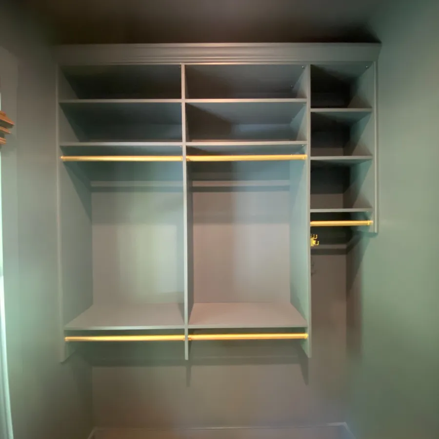 Modern, empty built-in shelving unit with multiple compartments in a gray room next to wooden flooring.
