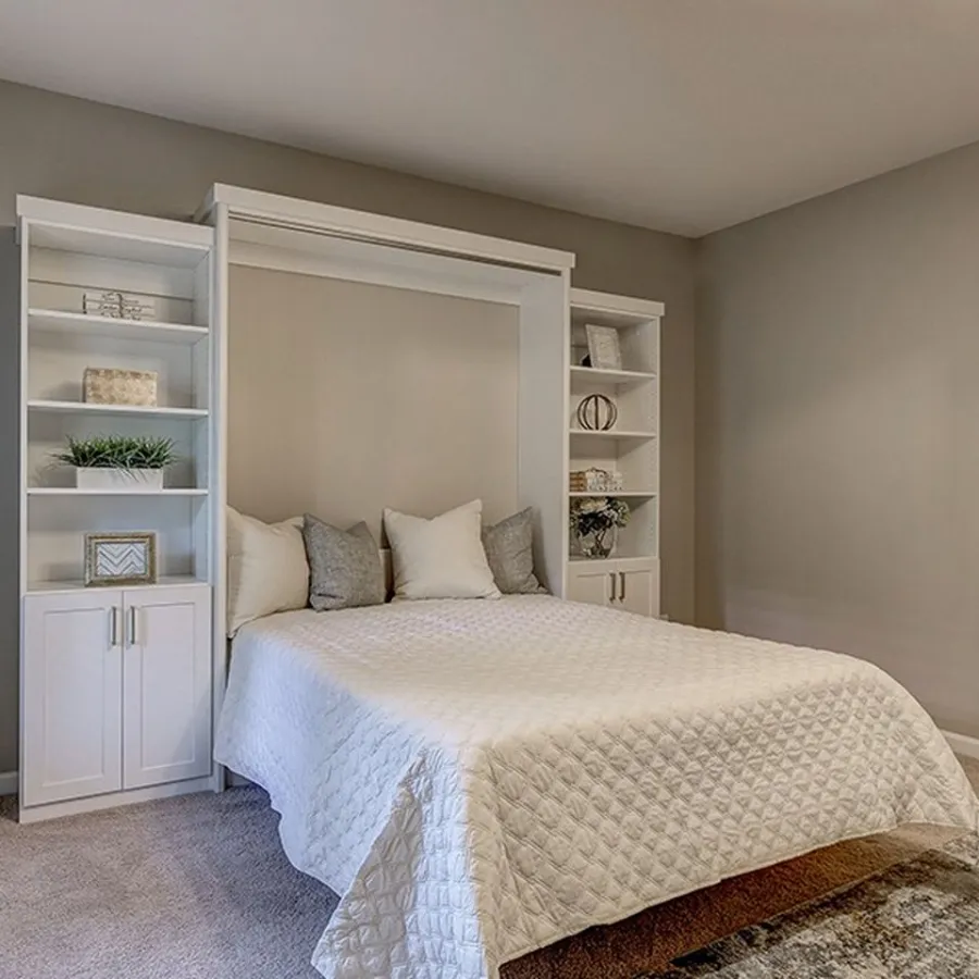 Minimalist bedroom with white Murphy bed, built-in shelves, neutral bedding, and abstract wall art on gray walls.