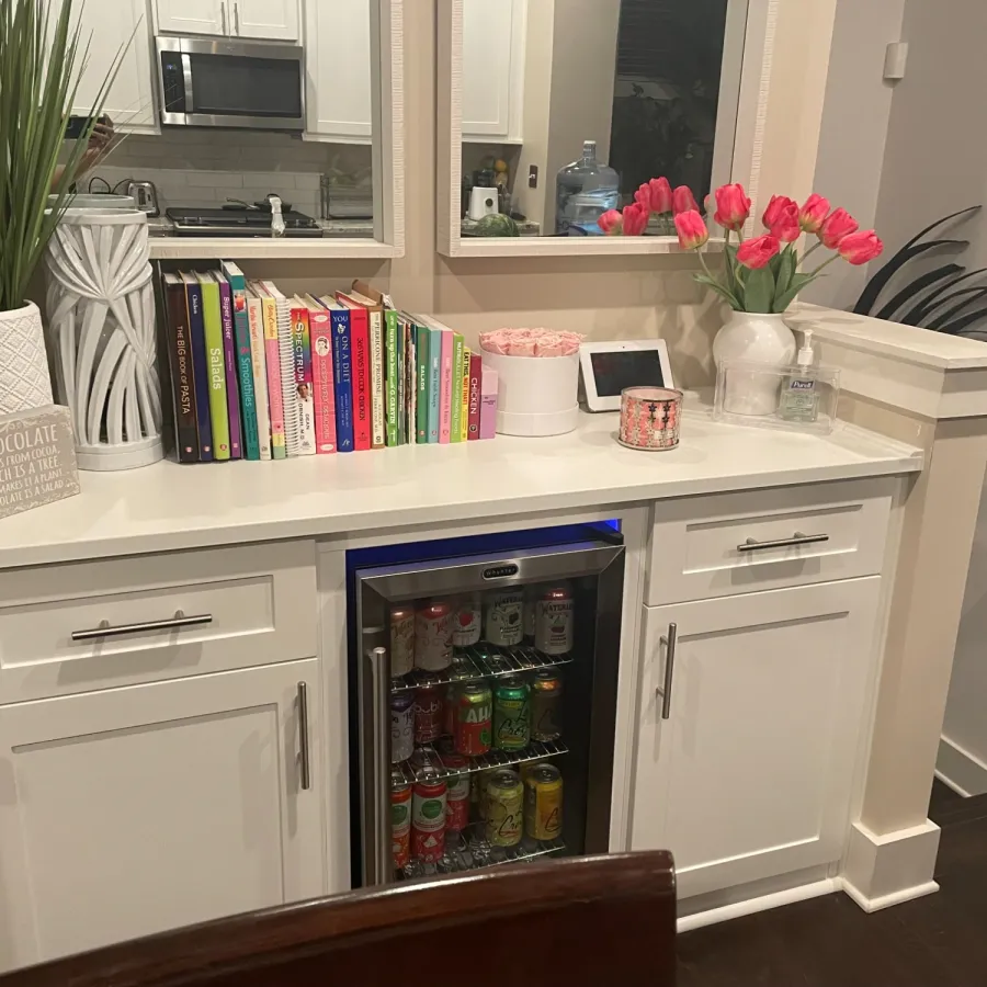 a white cabinet with a white top and a white counter top with a pink flower on it