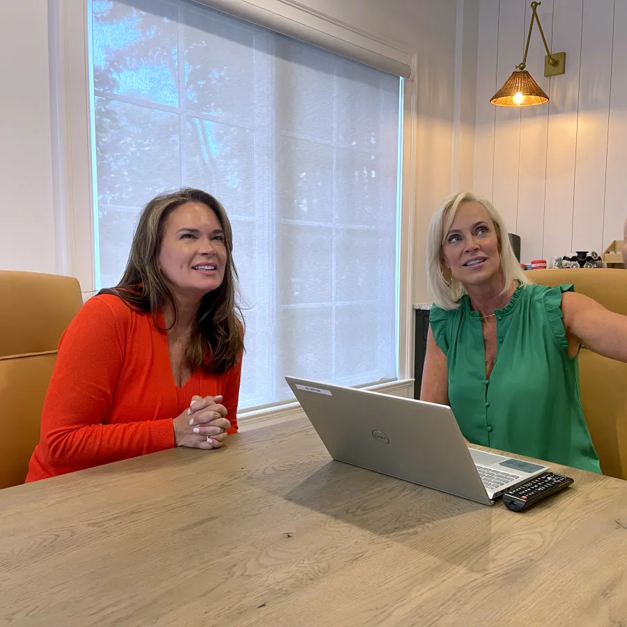 a couple of women sitting at a table with a laptop