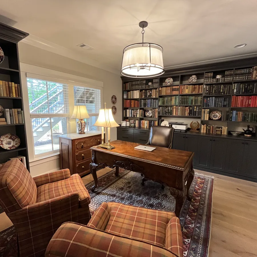 a living room with a desk and bookshelves